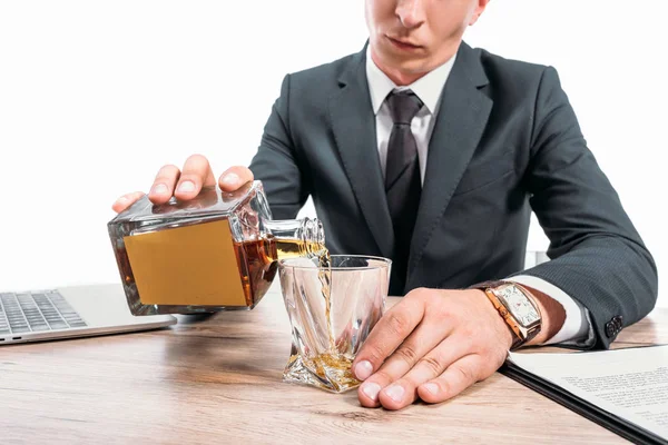 Imagen recortada de hombre de negocios vertiendo whisky en el vidrio en el espacio de trabajo aislado en blanco - foto de stock