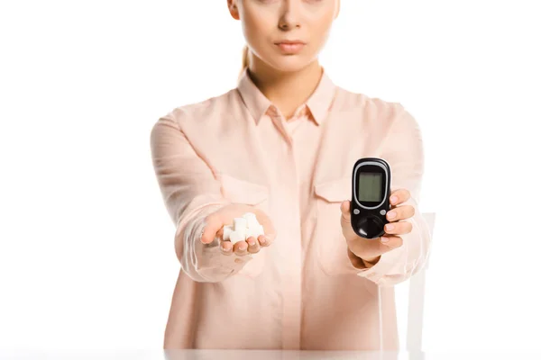 Imagem cortada de mulher segurando açúcar refinado e glicosímetro isolado no conceito de diabetes branco — Fotografia de Stock