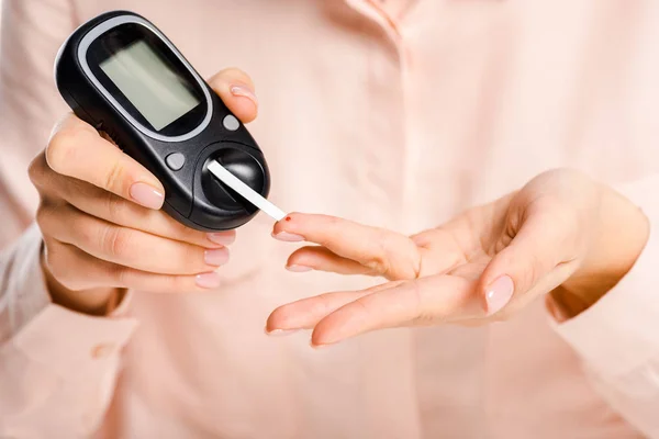 Ausschnittbild einer Frau, die den Glukosespiegel im Blut misst, mit einem Glukometer, das auf weiß isoliert ist, Diabetes-Konzept — Stockfoto