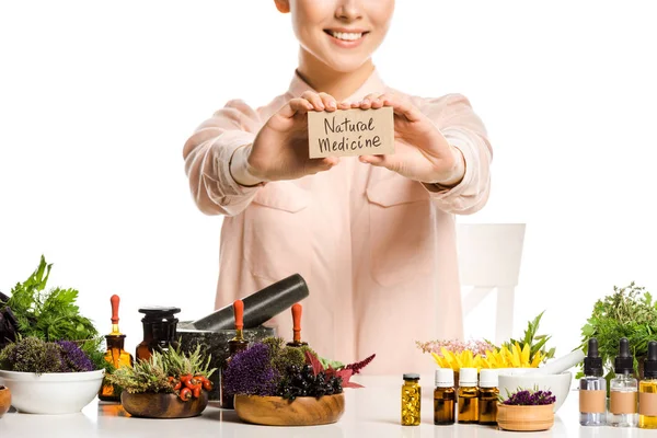Imagen recortada de la mujer que muestra la tarjeta con signo de medicina natural aislado en blanco - foto de stock