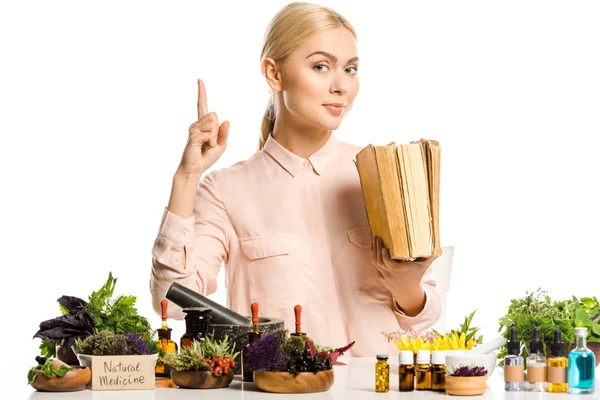 Atractiva mujer sosteniendo libros y señalando aislado en blanco, concepto de medicina natural - foto de stock