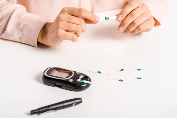 Imagen recortada de la mujer sosteniendo tira de glucosímetro aislado en blanco, concepto de diabetes - foto de stock