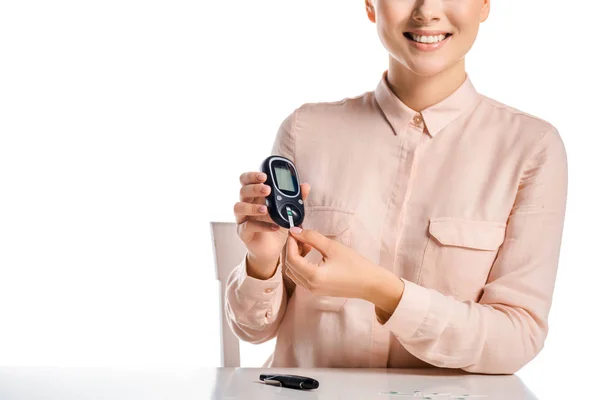 Imagen recortada de la mujer sonriente poniendo tira en el glucosímetro aislado en blanco, concepto de diabetes - foto de stock