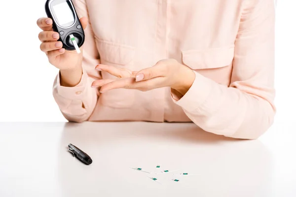 Imagem cortada de menina medindo nível de glicose no sangue com glicosímetro isolado em branco, conceito de diabetes — Fotografia de Stock