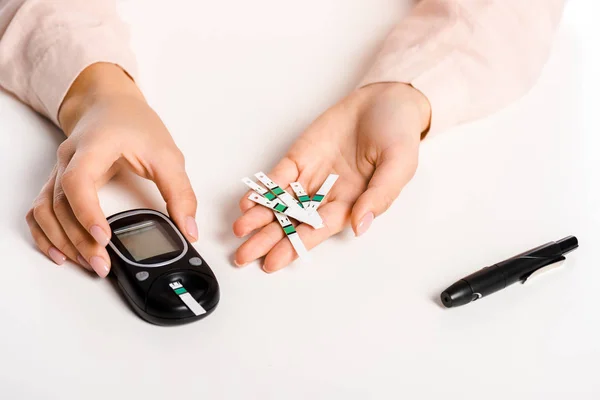 Imagem cortada de mulher segurando glicosímetro e tiras isoladas em branco, conceito de diabetes — Fotografia de Stock