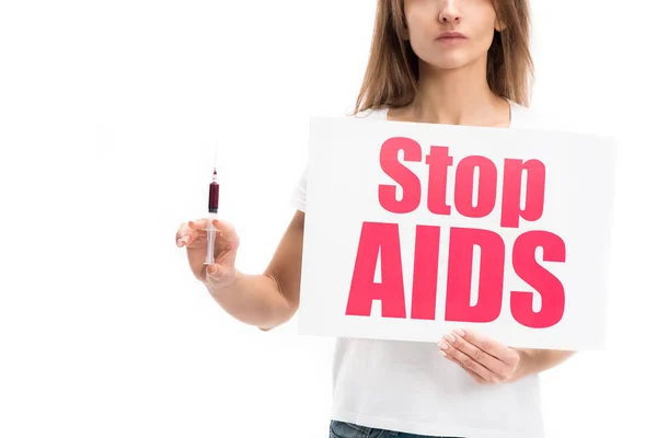 Imagen recortada de la mujer que sostiene la tarjeta con el texto de los stop aids y la jeringa aislados en blanco, concepto del día del sida mundial - foto de stock
