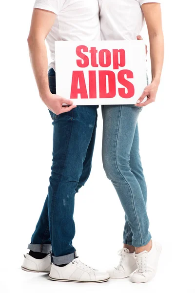 Imagen recortada de pareja heterosexual abrazando y sosteniendo la tarjeta con stop aids texto aislado en blanco - foto de stock