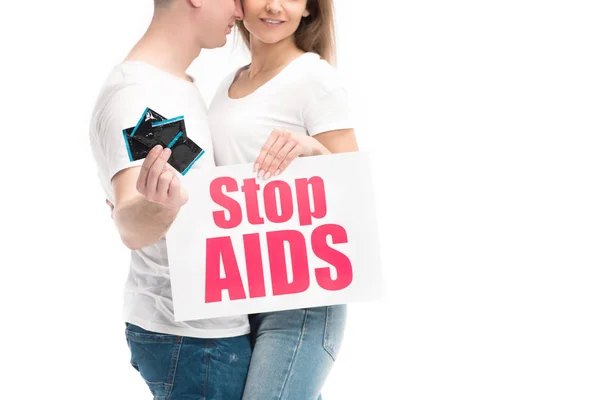 Cropped image of boyfriend showing condoms and girlfriend holding card with stop aids text isolated on white — Stock Photo