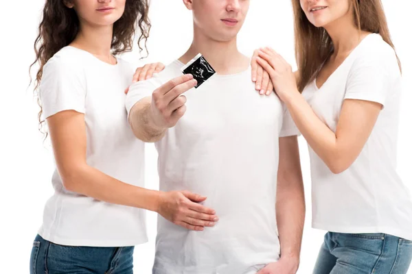 Cropped image of man showing condom, two girls hugging him isolated on white, world aids day concept — Stock Photo