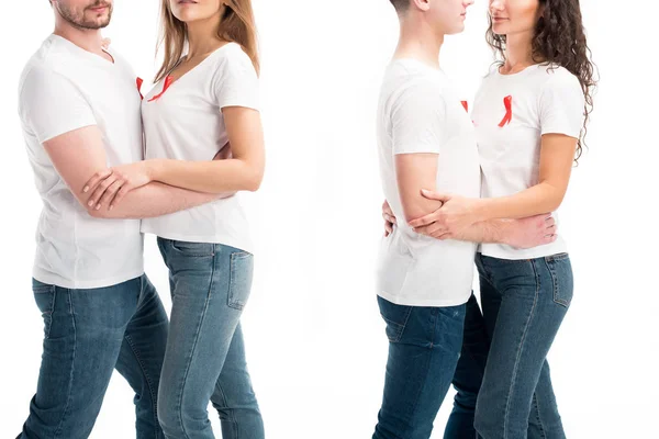 Imagen recortada de dos parejas heterosexuales con cintas rojas abrazándose aisladas en blanco, concepto del día del sida mundial - foto de stock