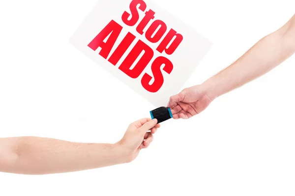 Image recadrée de petite amie et petit ami tenant préservatif, carte avec stop sida texte isolé sur blanc — Photo de stock