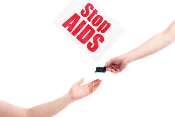 Cropped image of girlfriend giving condom to boyfriend, card with stop aids text isolated on white — Stock Photo