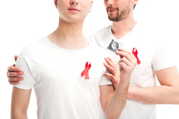 Imagem cortada de casal gay abraçando e segurando preservativo isolado no branco, mundo aids dia conceito — Fotografia de Stock