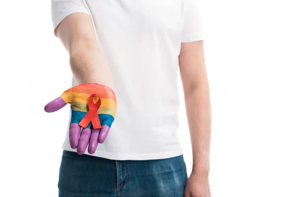 Imagem cortada de homem homossexual segurando fita vermelha na mão pintada em arco-íris isolado em branco, conceito de dia ajudas mundo — Fotografia de Stock