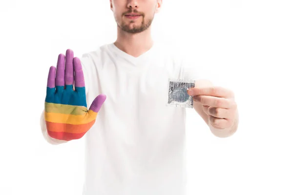 Immagine ritagliata di uomo omosessuale con dipinto a mano in arcobaleno tenendo preservativo isolato su bianco, concetto giorno aiuti mondo — Foto stock