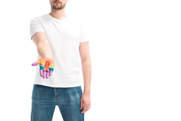 Image recadrée de l'homme tenant un ruban rouge à la main peint dans des couleurs de drapeau de fierté isolé sur blanc, concept de journée mondiale des aides — Photo de stock