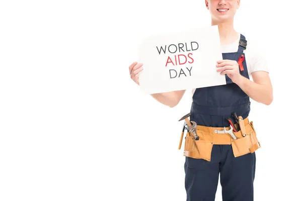 Cropped image of smiling worker in uniform and red ribbon showing card with world aids day text isolated on white — Stock Photo