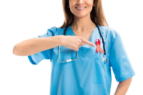Imagen recortada del médico sonriente apuntando a la cinta roja aislada en el concepto del día del sida blanco, mundial - foto de stock
