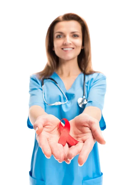 Sonriente atractivo médico sosteniendo cinta roja en manos aisladas en blanco, mundo SIDA concepto del día - foto de stock