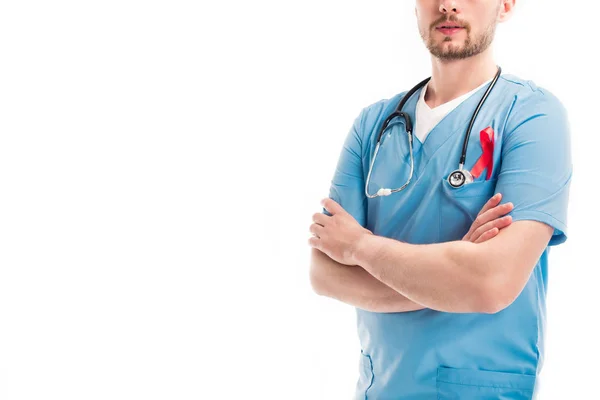 Abgeschnittenes Bild eines Arztes mit verschränkten Armen und roter Schleife auf Uniform isoliert auf weißem, Welt-Aids-Tag-Konzept — Stockfoto