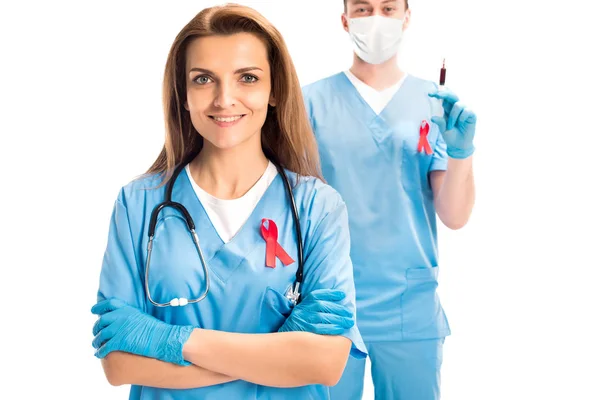 Doctors standing with red ribbons and syringe isolated on white, world aids day concept — Stock Photo