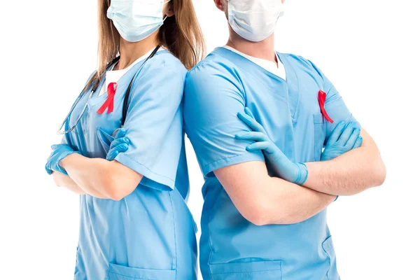 Cropped image of doctors with red ribbons and medical masks standing with crossed arms isolated on white, world aids day concept — Stock Photo