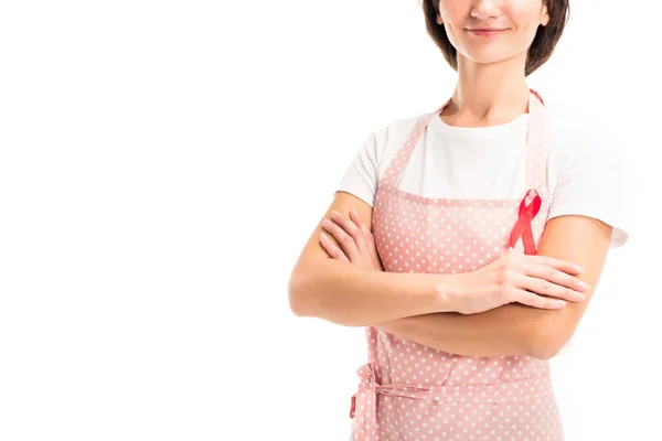 Cropped image of housewife in pink apron and red ribbon standing with crossed arms isolated on white, world aids day concept — Stock Photo