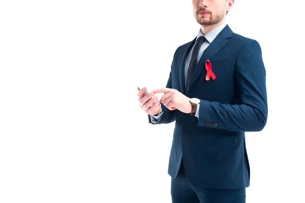 Image recadrée de l'homme d'affaires avec ruban rouge sur costume à l'aide d'un smartphone isolé sur blanc, concept de journée mondiale des aides — Photo de stock