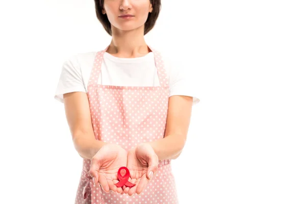 Cropped image of housewife in pink apron holding red ribbon in hands isolated on white, world aids day concept — Stock Photo