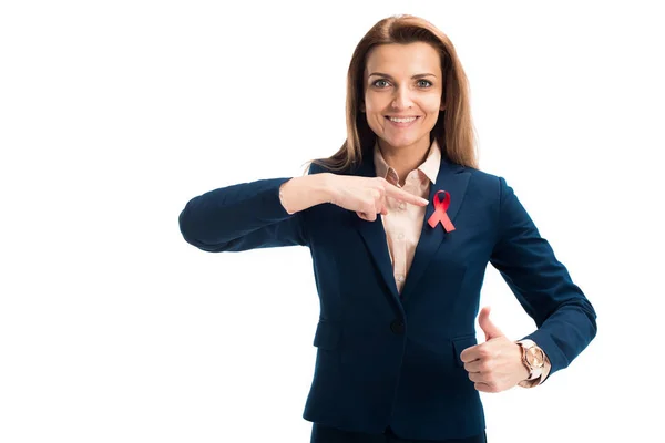 Lächelnde attraktive Geschäftsfrau zeigt auf rotes Band und zeigt Daumen hoch auf weißem, Welthilfetag-Konzept — Stockfoto