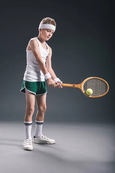 Preteen boy in sportswear with tennis racket and ball on dark background — Stock Photo