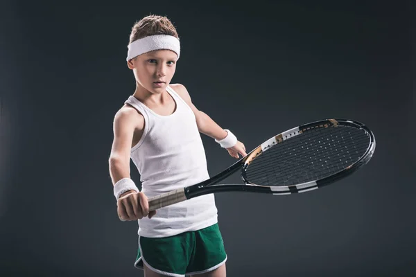 Retrato de niño en ropa deportiva con raqueta de tenis sobre fondo oscuro - foto de stock