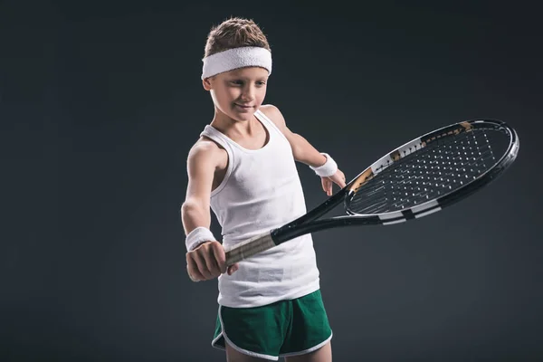 Retrato de niño en ropa deportiva con raqueta de tenis sobre fondo oscuro - foto de stock