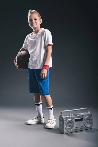 Garçon élégant avec ballon de basket et boombox sur fond gris — Photo de stock