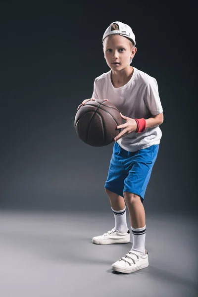 Stylish boy playing basketball on grey background — Stock Photo