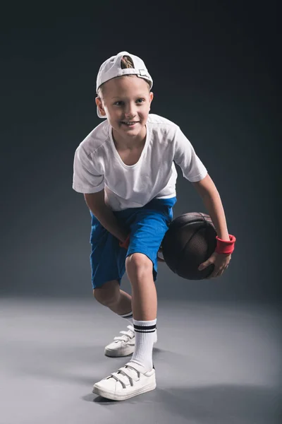 Menino elegante jogando basquete no fundo cinza — Fotografia de Stock