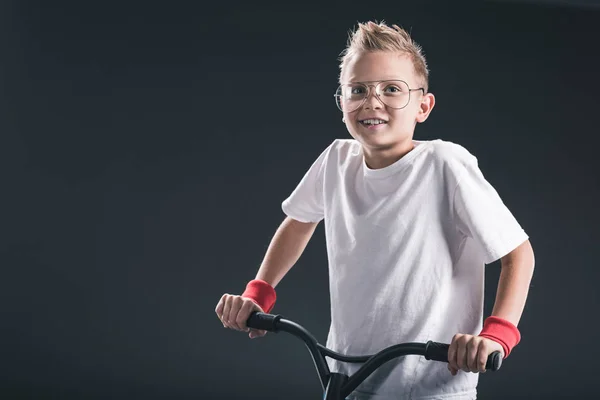 Portrait of stylish boy in eyeglasses with scooter on black backdrop — Stock Photo