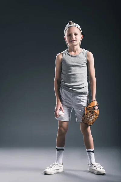 Menino pré-adolescente em boné com luva de beisebol e bola no fundo cinza — Fotografia de Stock