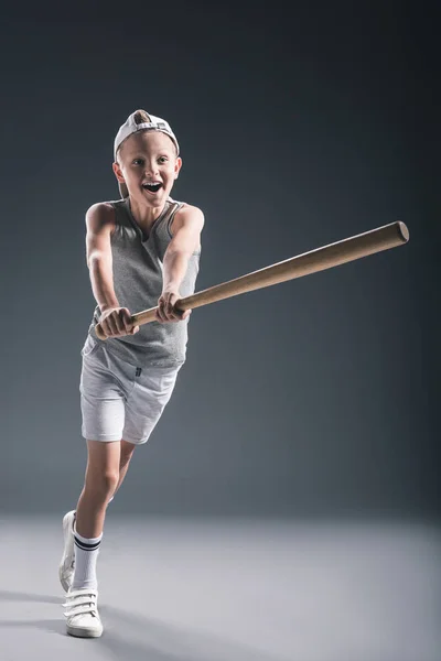 Niño preadolescente emocional en gorra con bate de béisbol sobre fondo gris - foto de stock