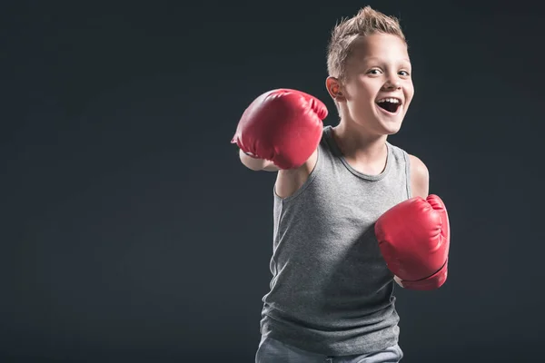 Portrait of cheerful boy with red boxing gloves on black backdrop — Stock Photo