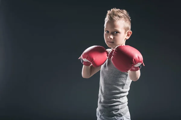 Portrait of boy with red boxing gloves on black backdrop — Stock Photo