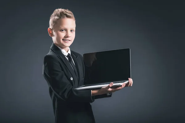 Retrato de pequeno empresário mostrando laptop com tela em branco no fundo cinza — Fotografia de Stock