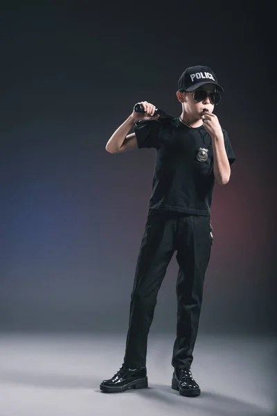 Junge in Polizeiuniform und Sonnenbrille mit Trillerpfeife auf dunklem Hintergrund — Stockfoto