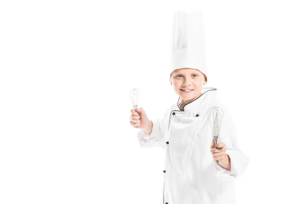 Portrait of smiling pre-adolescent boy in chef uniform and hat with whisks isolated on white — Stock Photo