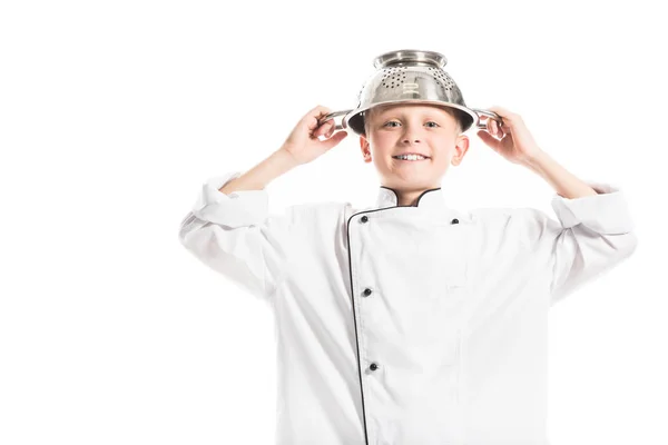 Portrait de garçon préadolescent en uniforme de chef blanc avec passoire sur la tête isolé sur blanc — Photo de stock