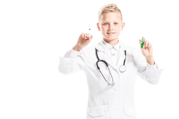 Retrato del niño preadolescente en la bata blanca de los médicos con estetoscopio, medicina y jeringa aislados en blanco - foto de stock