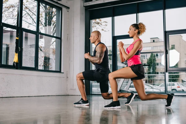 Feliz joven afroamericano pareja de atletas haciendo ejercicio en el gimnasio - foto de stock