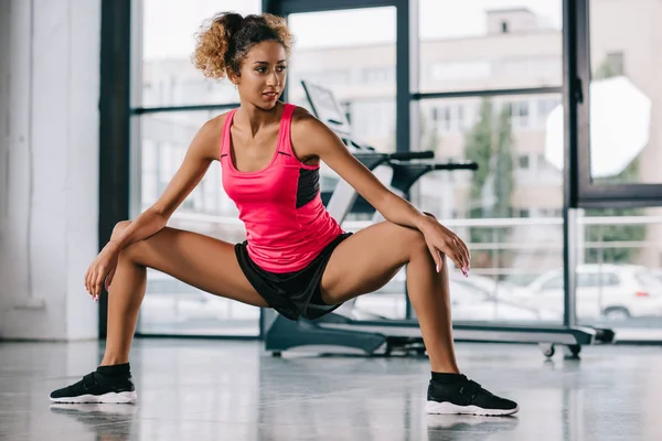 Attractive young african american female athlete doing exercise at gym — Stock Photo
