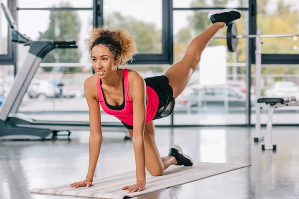 Selektiver Fokus einer afrikanisch-amerikanischen Sportlerin, die im Fitnessstudio auf Fitnessmatten trainiert — Stockfoto