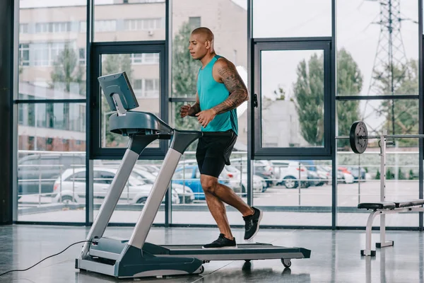 Vista laterale del giovane sportivo afroamericano che corre sul tapis roulant in palestra — Foto stock